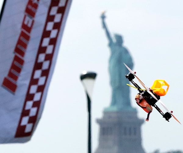 a racing drone flies with the statue of liberty in the background