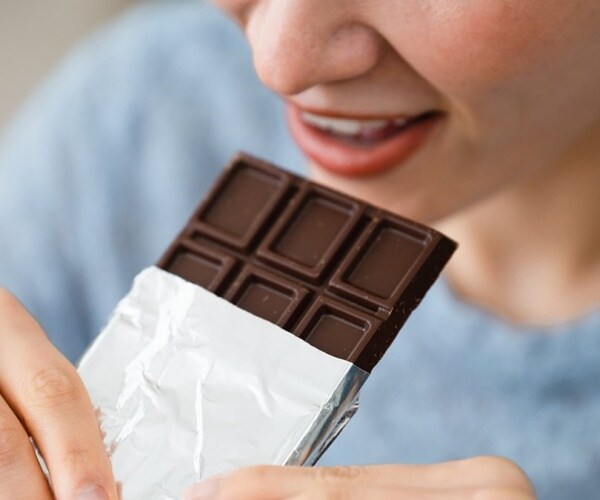 woman eating a bar of dark chocolate