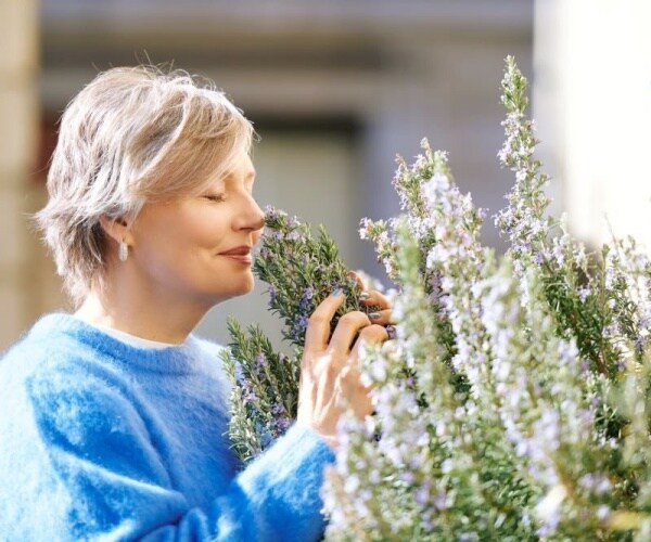 older woman outside smelling lavendar