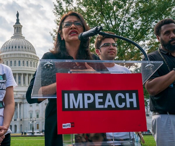 rashida tlaib speaks at a podium in front of the capitol dome about impeachment