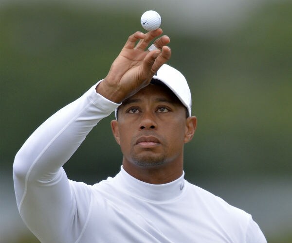 tiger woods tosses a golf ball in the air