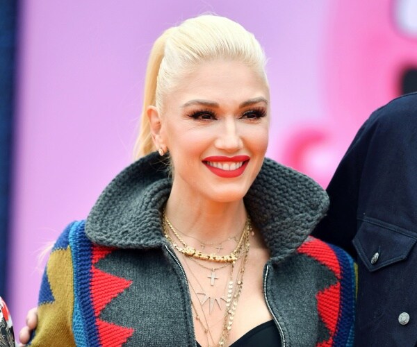 stefani in a gray coat with gold necklaces and red lipstick