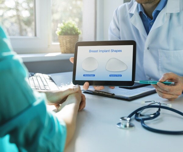 doctor explaining to patient options for breast implants using a tablet