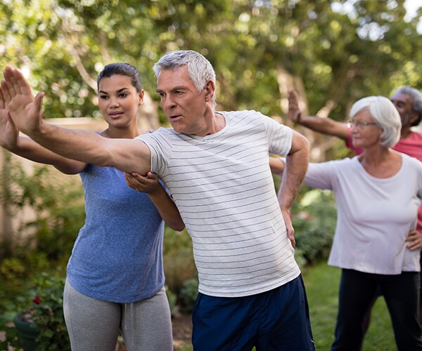 senior adults doing yoga outside in the morning with an instructor