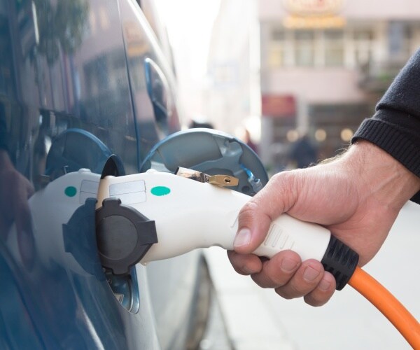 man charging an electric car at charging station