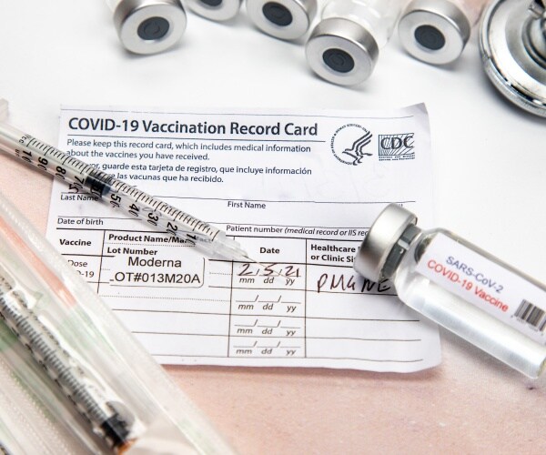 CDC COVID vaccine record card, vial of COVID vaccine, syringes