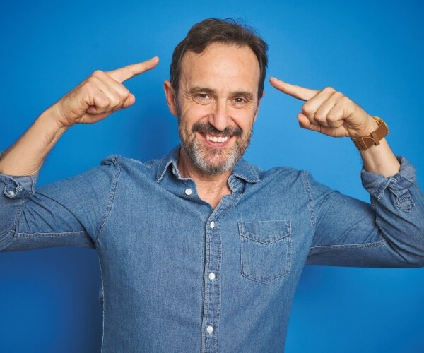 man smiling and pointing to his head with both hands