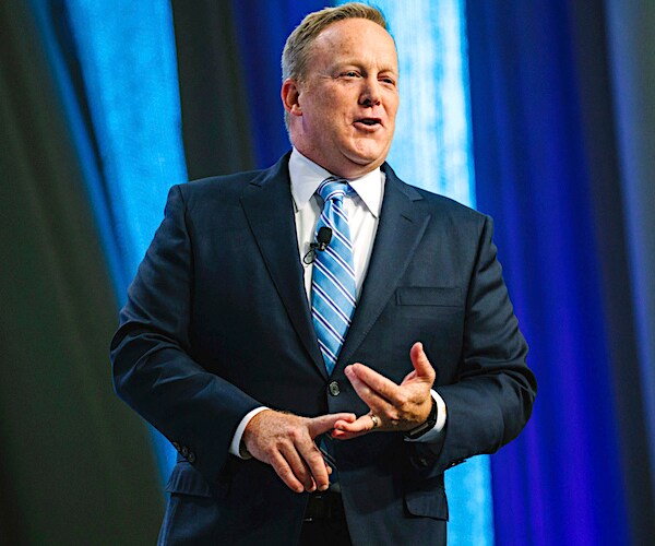 sean spicer gestures with his hands while speaking during a convention