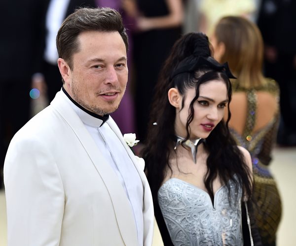 elon musk in white formal jacket with singer grimes in bustier style top standing at his left at new york city gala