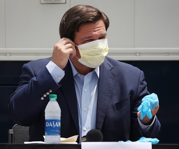 gov. ron desantis removes a mask to speak at a press conference