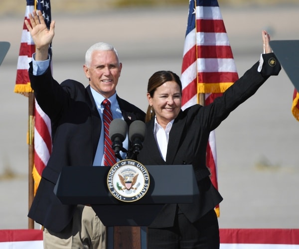 mike and karen pence wave while arm-in-arm behind a podium