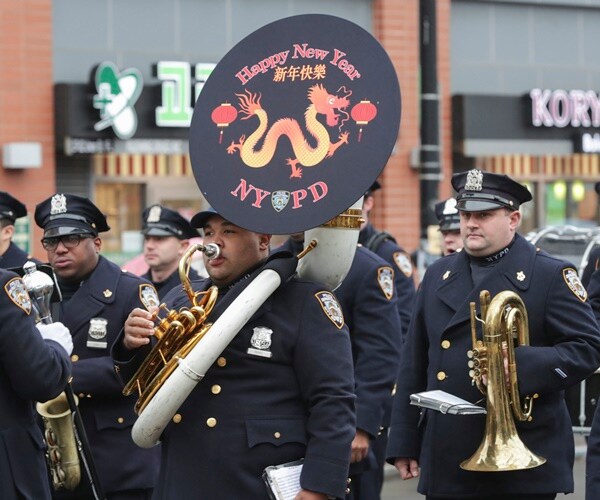 a police officer carries a tuba, others with a horn, sax,  in an nypd marching band 