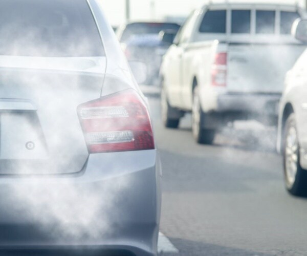 cars on highway with smoke coming out of tailpipes 