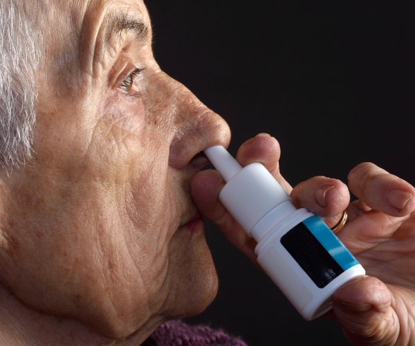 Elderly woman using nasal spray