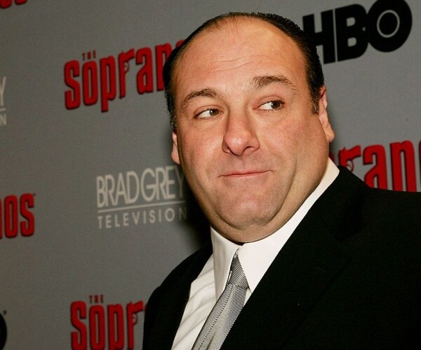 closeup of james gandolfini with the sopranos logo in background