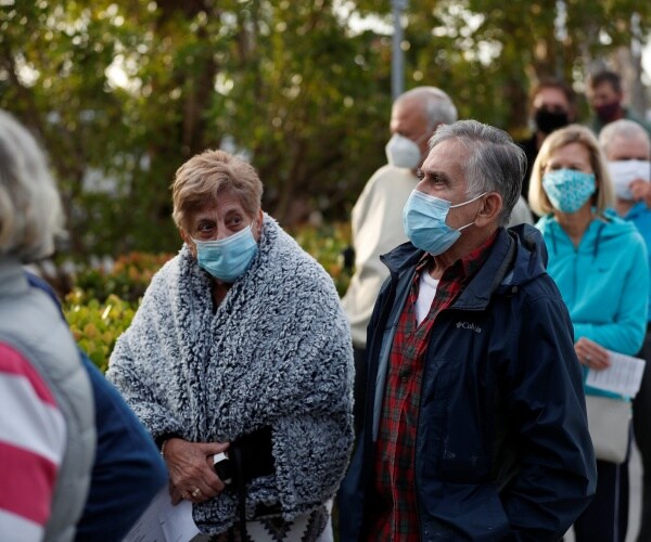 seniors wear masks and wait in a line to get the vaccine