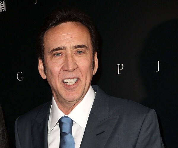 nicolas cage stands on red carpet