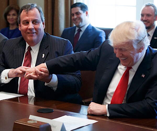 chris christie holds the right hand of president donald trump between his two hands while the president is laughing