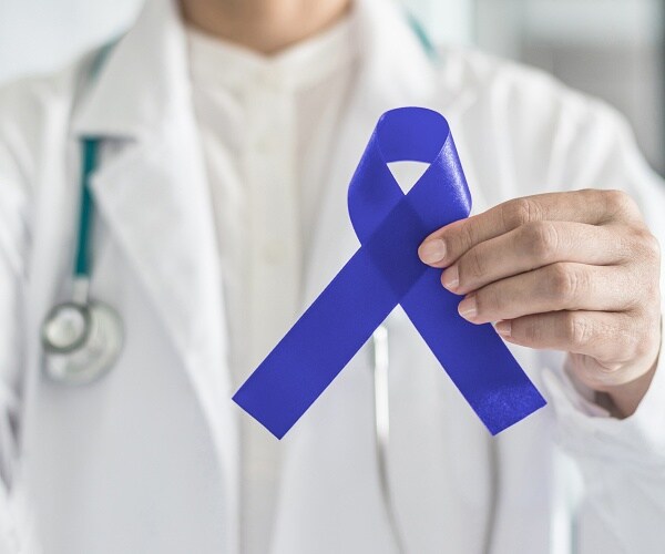 doctor in white lab coat holding blue ribbon