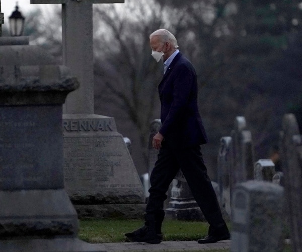 joe biden walks through a cemetary