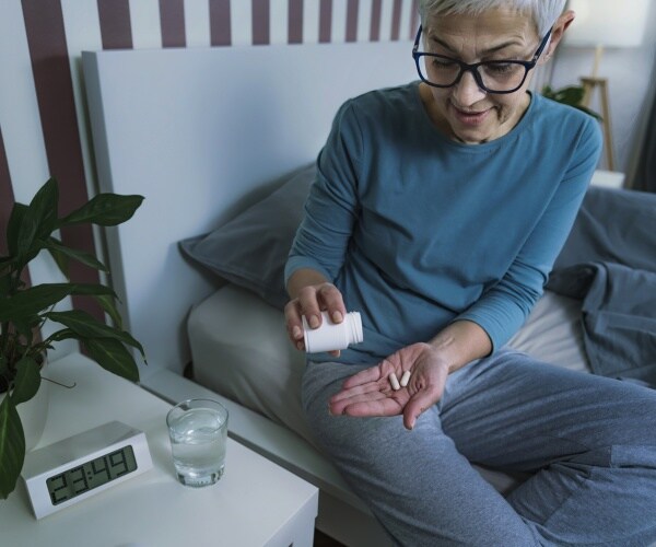 woman in bed taking sleep medication before going to sleep