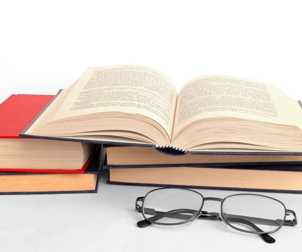 a stack of books and a pair of glasses folded up