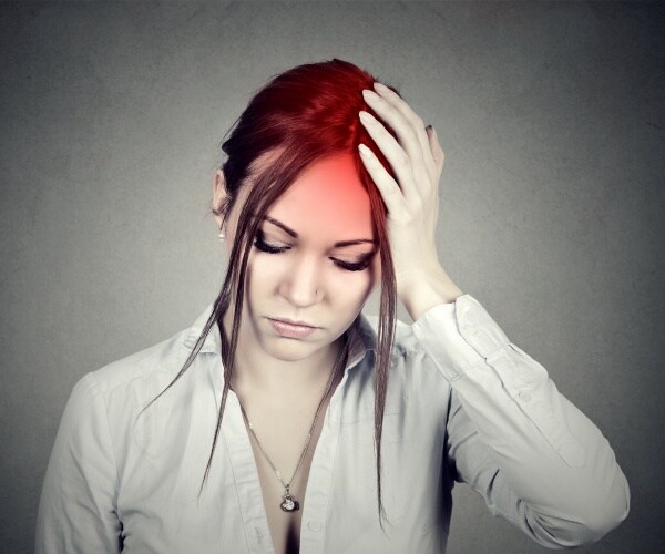 woman holding her head with a headache, red highlighting where it hurts