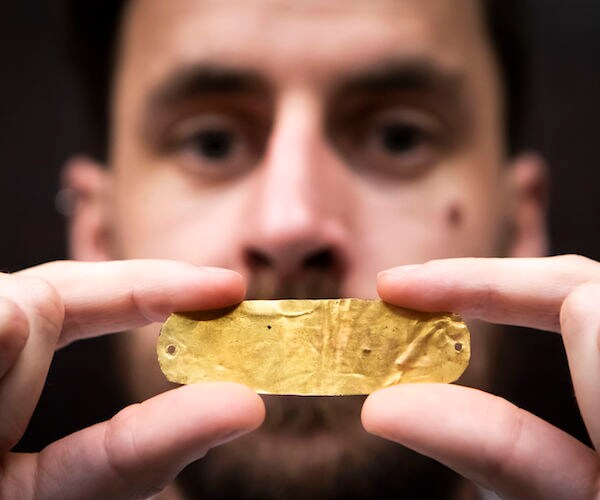 close-up of a third century golden mouth plaque held by a museum curator