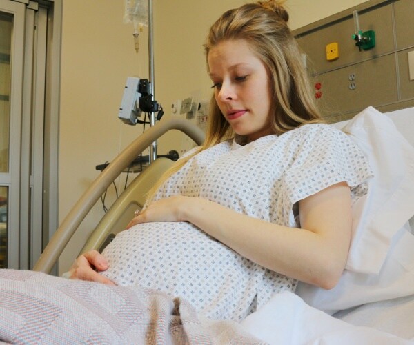 pregnant woman in hospital bed looking concerned