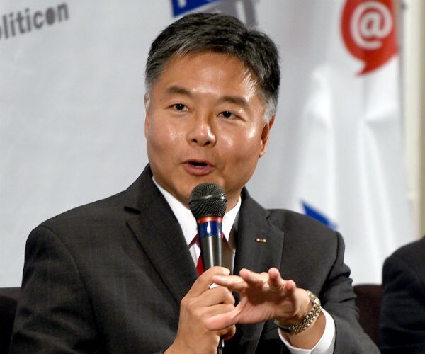 california democratic representative ted lieu looks to his right and speaks into a mic during a news conference