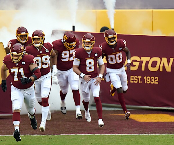 the washington football team in the burgandy rushes onto the field