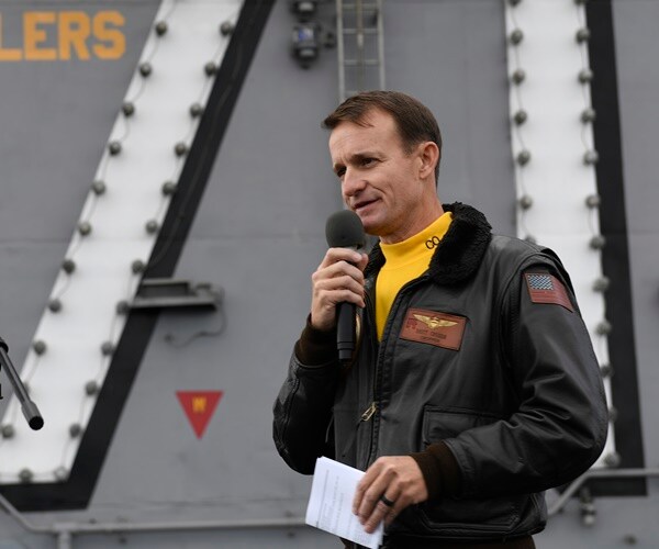 captain brett crozier holds a mic addressing the crew of the uss teddy roosevelt