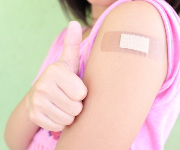 young child with thumbs up and band-aid on arm