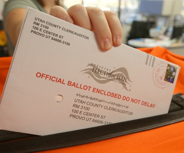 envelopes with official ballots enclosed are put inside an orange box by a poll worker