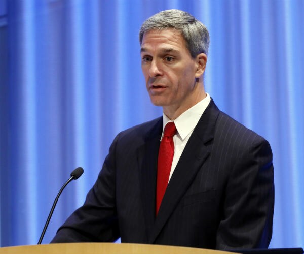 ken cuccinelli is seen in a dark suit, white dress shirt and red tie