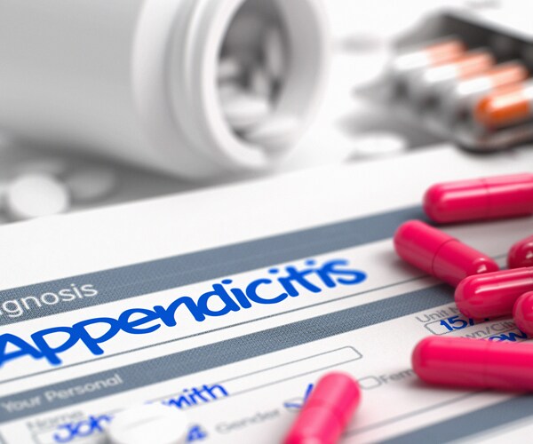 the word appendicitis written on a piece of paper with red pills