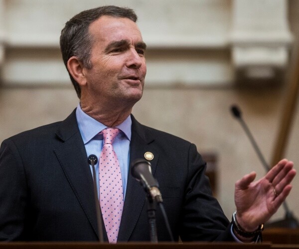 ralph northam speaking wearing a pink tie, blue shirt and black suit