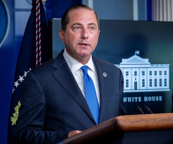 alex azar stands behind podium in briefing room