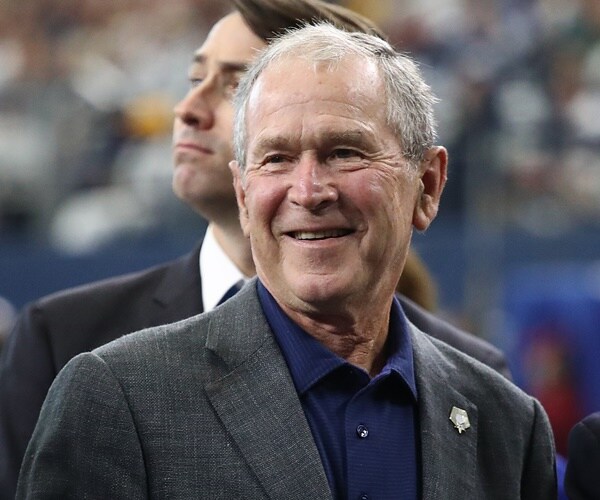 george w. bush walks across a football fields