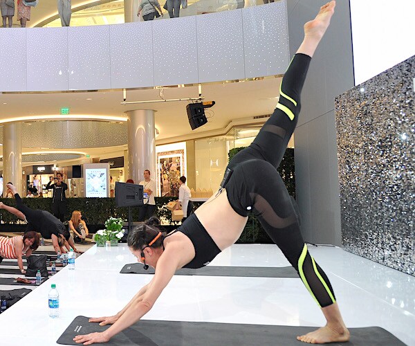 a woman stretches her leg up high in the air behind her as she places his palms on the ground in front of her