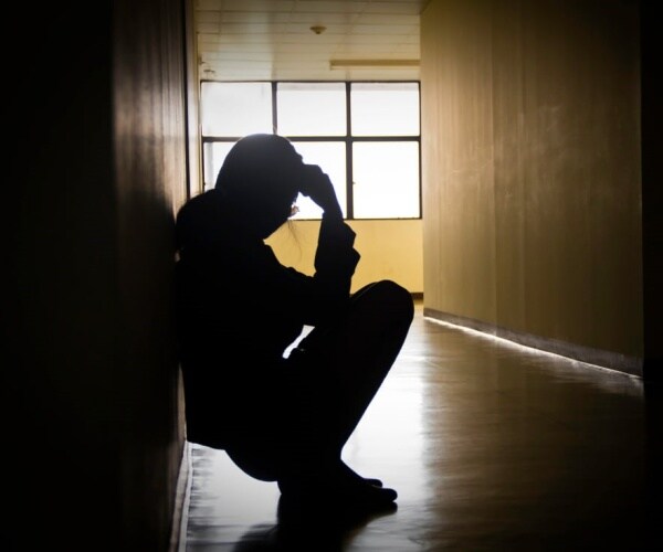 depressed person squatting down in hall