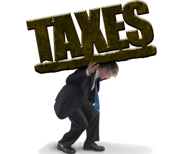 a man in a suit stooped down carrying the word taxes on his back