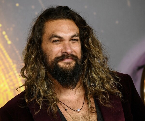 jason momoa stands on red carpet