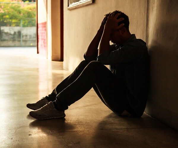 man sitting on floor with head in hands