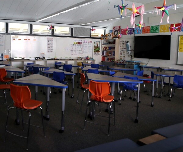 classroom with triangular desks and orange chairs is empty