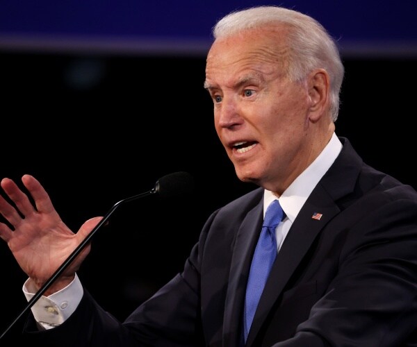 biden in a black suit and blue tie on the debate stage