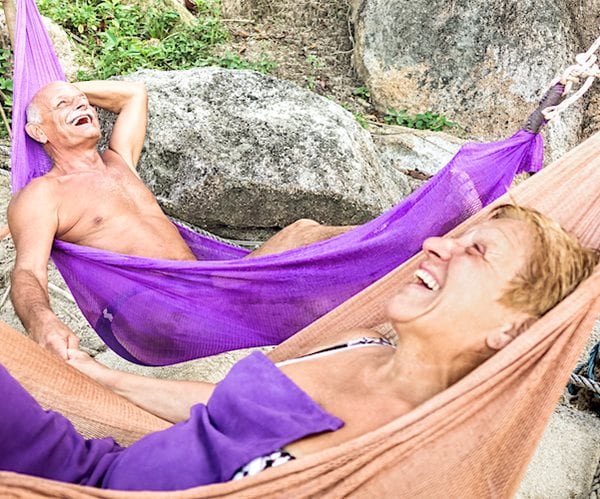 Senior retired couple vacationer relaxing on hammock at beach