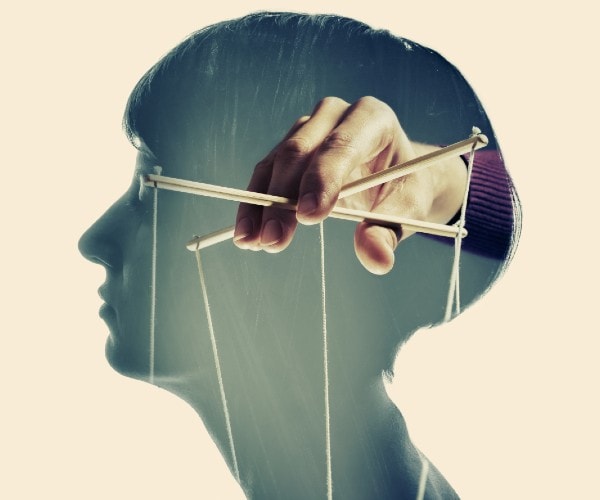 profile of a woman with a hand holding puppet strings inside her head