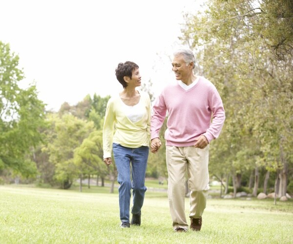 older couple walking, smiling in a park