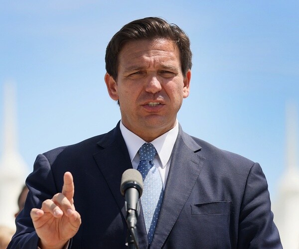 ron desantis speaks from behind podium on dock